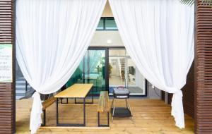 慶州市にあるPatio Pool Villaの白いカーテン、テーブル、ベンチが備わる客室です。
