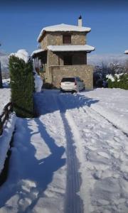 une voiture garée devant une maison dans la neige dans l'établissement Mountain View - Full Villa, à Polydrossos