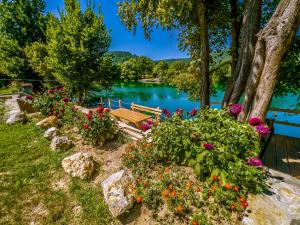 um banco de parque sentado ao lado de um rio com flores em Daman Villa em Bihać