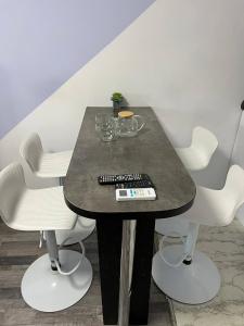 een tafel met witte stoelen en een afstandsbediening bij ITB Apartments Молодёжный in Alma-Ata