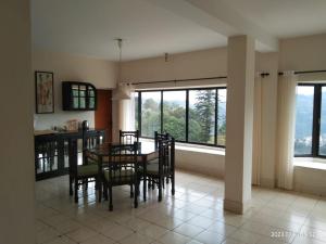 a dining room with a table and chairs and windows at Camellia Heights 1&2 in Coonoor