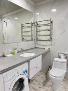 een badkamer met een wasmachine en een wastafel bij ITB Apartments Молодёжный in Alma-Ata