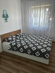 a bed with a black and white comforter and a window at Apartament Anna in Leszno