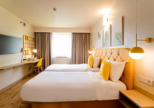 Cette chambre comprend deux lits et un bureau. dans l'établissement Bloom Hotel - Jammu, à Jammu
