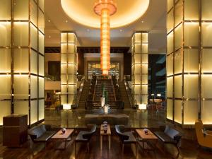 a lobby with tables and chairs and a large chandelier at Hilton Kuala Lumpur in Kuala Lumpur