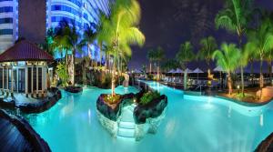 a large swimming pool at a resort at night at Hilton Kuala Lumpur in Kuala Lumpur