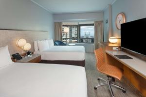 a hotel room with two beds and a flat screen tv at New York Hilton Midtown in New York +72 photos