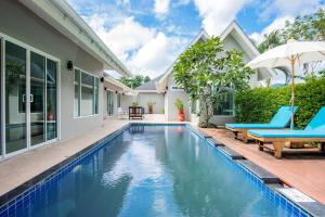 een zwembad in de achtertuin van een huis met blauwe stoelen en een parasol bij Colorful Pool Villa in Ban Chin Tham Mai