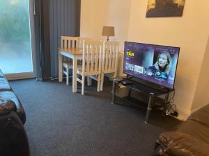 a living room with a television and a dining room table at 4 Bed: 5mins frm Wembley Stadium in London