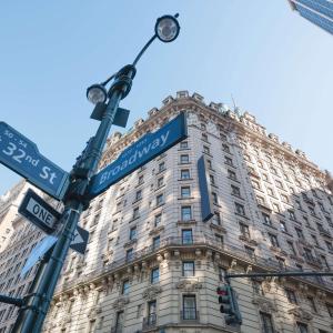 una luz de la calle con letreros delante de un edificio en Martinique New York on Broadway, Curio Collection by Hilton en Nueva York