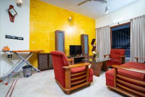 a living room with yellow walls and red chairs at SS Mystic Apartotel in Bangalore