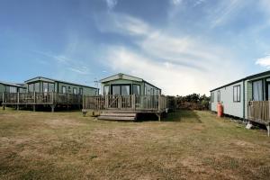a row of green camping huts in a field at Caravan with sea views on the coast near St Davids in Pembrokeshire