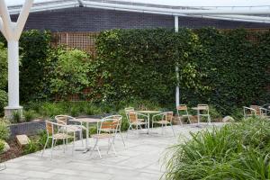 a patio with chairs and tables and a hedge at Aparthotel Adagio London Brentford in Brentford +56 photos