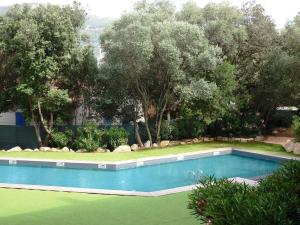 a swimming pool in a yard with trees at Appartement Cité Du Sel in Porto-Vecchio
