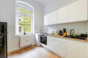 een witte keuken met witte kasten en een raam bij unique Malterstraße feel-good-home - Dresden in Dresden