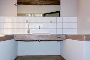 a bathroom with a sink in a white tiled wall at At Kronenhof Campsites in Sesriem