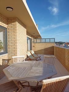 eine Terrasse mit einem Holztisch und Stühlen auf dem Balkon in der Unterkunft Sunset Lounge CorgoMar in Lavra