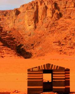 a building in the middle of a desert with a mountain at Bedouin bunch camp in Wadi Rum