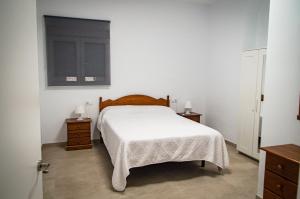 a bedroom with a white bed and two night stands at Casa vacacional El Sol in Turís