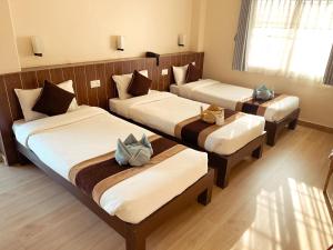 a hotel room with three beds in a room at Pokhara Tourist Home in Pokhara