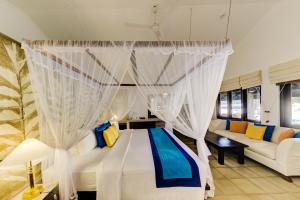 - une chambre avec un lit avec des rideaux et un canapé dans l'établissement Habarana Village by Cinnamon, à Habarana