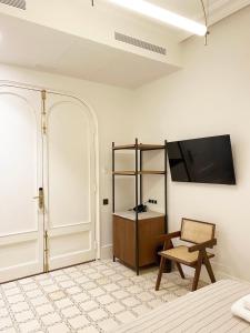 a room with a tv on the wall and a chair at Casa Llimona Hotel Boutique in Barcelona