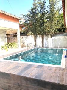 einen Pool mit einer Holzterrasse und einem Pool in der Unterkunft Casa espaçosa com Piscina e Churrasqueira 2 dorm in Guarujá
