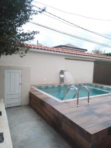 a swimming pool with a wooden deck and a bathtub at Casa espaçosa com Piscina e Churrasqueira 2 dorm in Guarujá