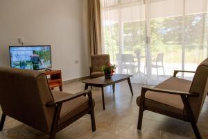a living room with chairs and a tv and a table at Macmillan's Holiday Villas in Grand'Anse Praslin