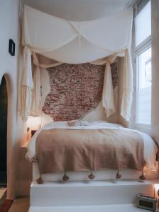 een slaapkamer met een hemelbed en een bakstenen muur bij HAERT Boutique Wellness Suites City Centre in Haarlem