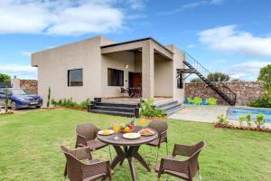 a house with a table and chairs in the yard at StayVista's La Villa Farm - Tranquil Retreat with Outdoor Pool, Games & Terrace in Mohāna