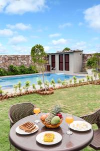 a table with a bowl of food and glasses of wine at StayVista's La Villa Farm - Tranquil Retreat with Outdoor Pool, Games & Terrace in Mohāna