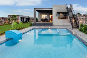 a swimming pool in front of a house at StayVista's La Villa Farm - Tranquil Retreat with Outdoor Pool, Games & Terrace in Mohāna