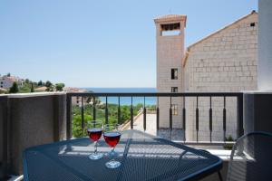 two glasses of red wine sitting on a table on a balcony at Luxurious Apartments Maslina with Beach in Milna