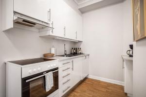 a kitchen with white cabinets and a stove top oven at Rosen Apartment in Bergen