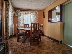 a dining room with a table and chairs and a window at Mara bush house in Sekenani