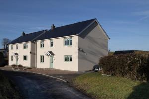 una casa bianca con tetto nero e vialetto di Family Country Cottage with Stunning Mountain View sleeps 12 a Myddfai
