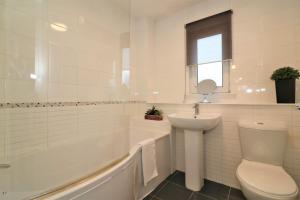 a white bathroom with a sink and a toilet and a tub at Signature - Angus House Glasgow in Glasgow +32 photos