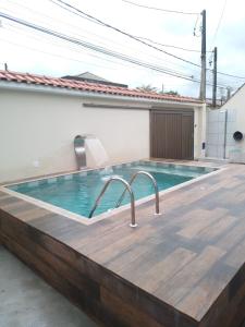 uma piscina com um deque de madeira e uma piscina com um centro de leitura de piscina em Casa espaçosa com Piscina e Churrasqueira 2 dorm no Guarujá