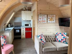 una sala de estar con sofá en una casa pequeña en Squirrel Glamping Pod School House Farm en Leighton