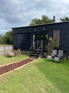 a black building with two chairs and a playground at Oak Tree Lodge: Unique 2 level Shepherd's Hut: Dartmouth in Dartmouth