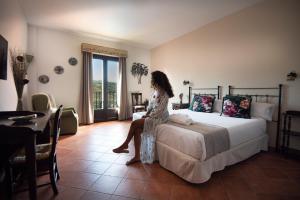 a woman sitting on a bed in a room at Hotel Boutique Cerro del Sol in Cenes de la Vega