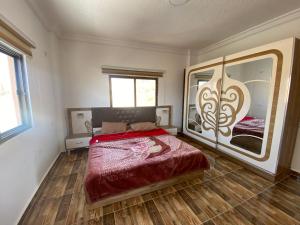 Jar AlQamar Chalet -شاليه جار القمر في جرش: غرفة نوم بسرير ومرآة كبيرة