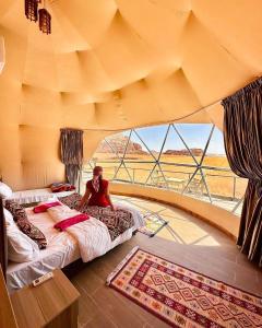 a person sitting on a bed in a room with a window at Wadirum winter in Wadi Rum