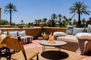 eine Terrasse mit einem Sofa, einem Tisch und Palmen in der Unterkunft Les Jardins de Skoura in Skoura