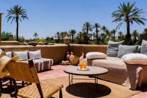a patio with a couch and a table and palm trees at Les Jardins de Skoura in Skoura