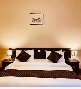 sypialnia z łóżkiem z poduszkami i zdjęciem na ścianie w obiekcie Hotel Dorjiling w mieście Paro