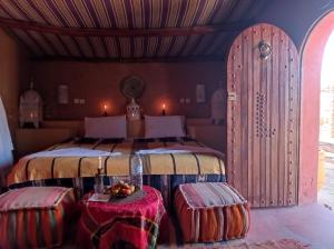 una camera da letto con un letto con due tavoli davanti di Desert Bivouac Mhamid a M'Hamid