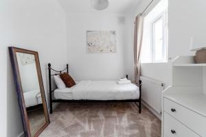 a white bedroom with a mirror and a bed at Fantastic 2BR flat wgarden, West Norwood in West Dulwich