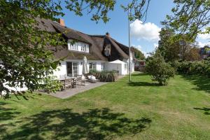 ein Haus mit Strohdach und einem Garten in der Unterkunft Kapitänshaus West in Oldsum